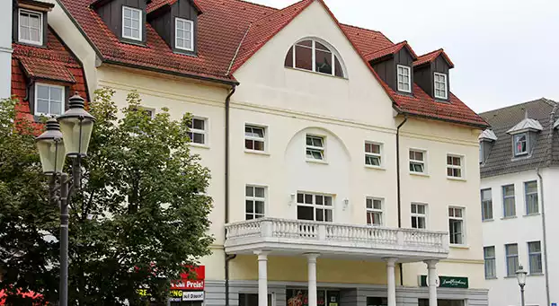 Helles mehrstöckiges Gebäude mit Balkon auf Säulen im 1. Stock