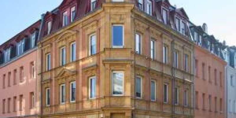 Eckansicht eines mehrstöckigen Wohnhauses mit historischer Fassade.
