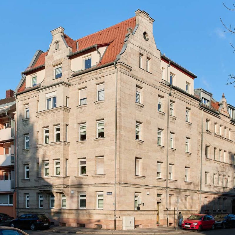 Seitliche Ansicht auf mehrtöckiges Wohngebäude mit Sandsteinfassade.