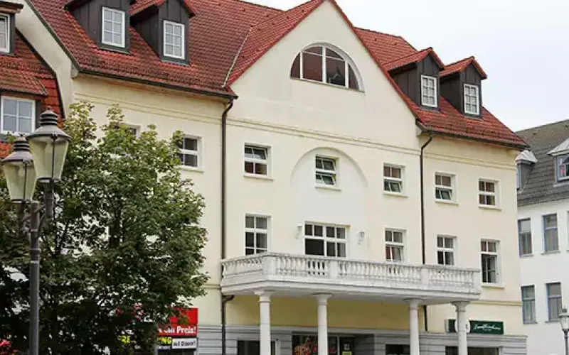 Helles mehrstöckiges Gebäude mit Balkon.