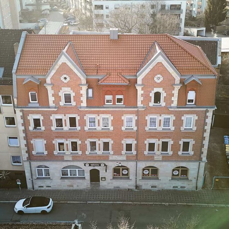Kreuzsteinstraße 26, Nürnberg, mehrstöckiges Wohngebäude mit roter Fassade, Drohnenaufnahme vorne